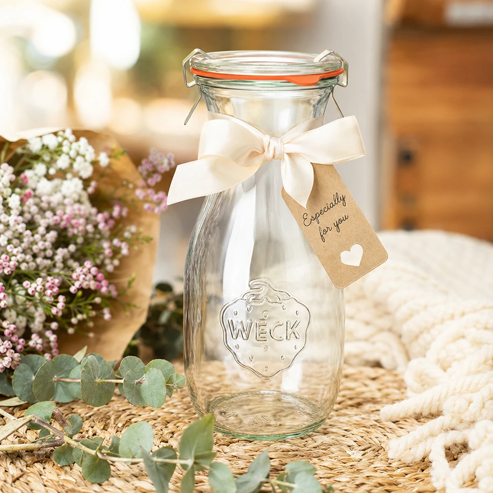 Bouteille à jus de 530 ml, ensemble complet WECK RR60 WECK Bouteille de jus de fruit de 530 ml RR60 décorée avec un ruban blanc et une étiquette cadeau arrangée entre des fleurs
