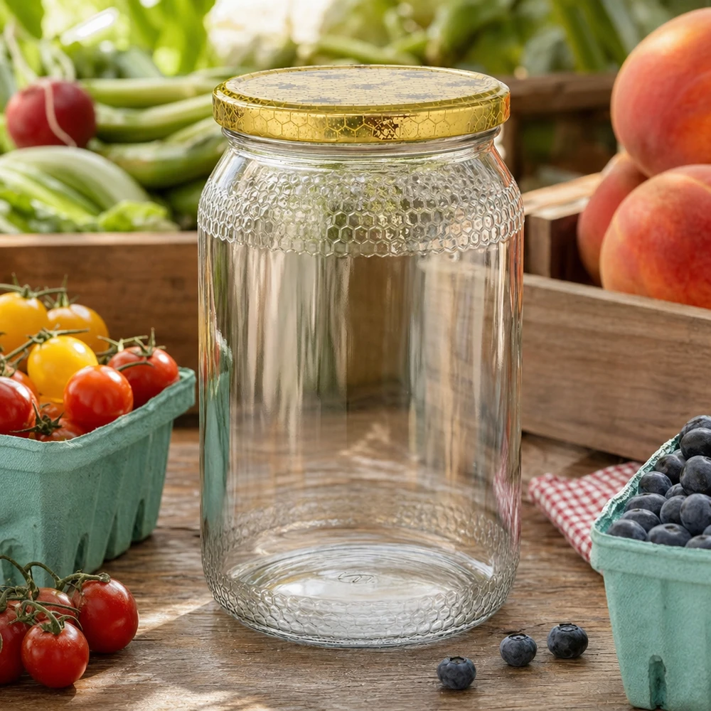Pot à miel 1260 g avec couvercle motif rayon de miel BasicSeal UNiTWIST Pot de miel de 900ml vide avec couvercle doré en nid d'abeille entre des fruits et légumes frais sur une table de cuisine en bois