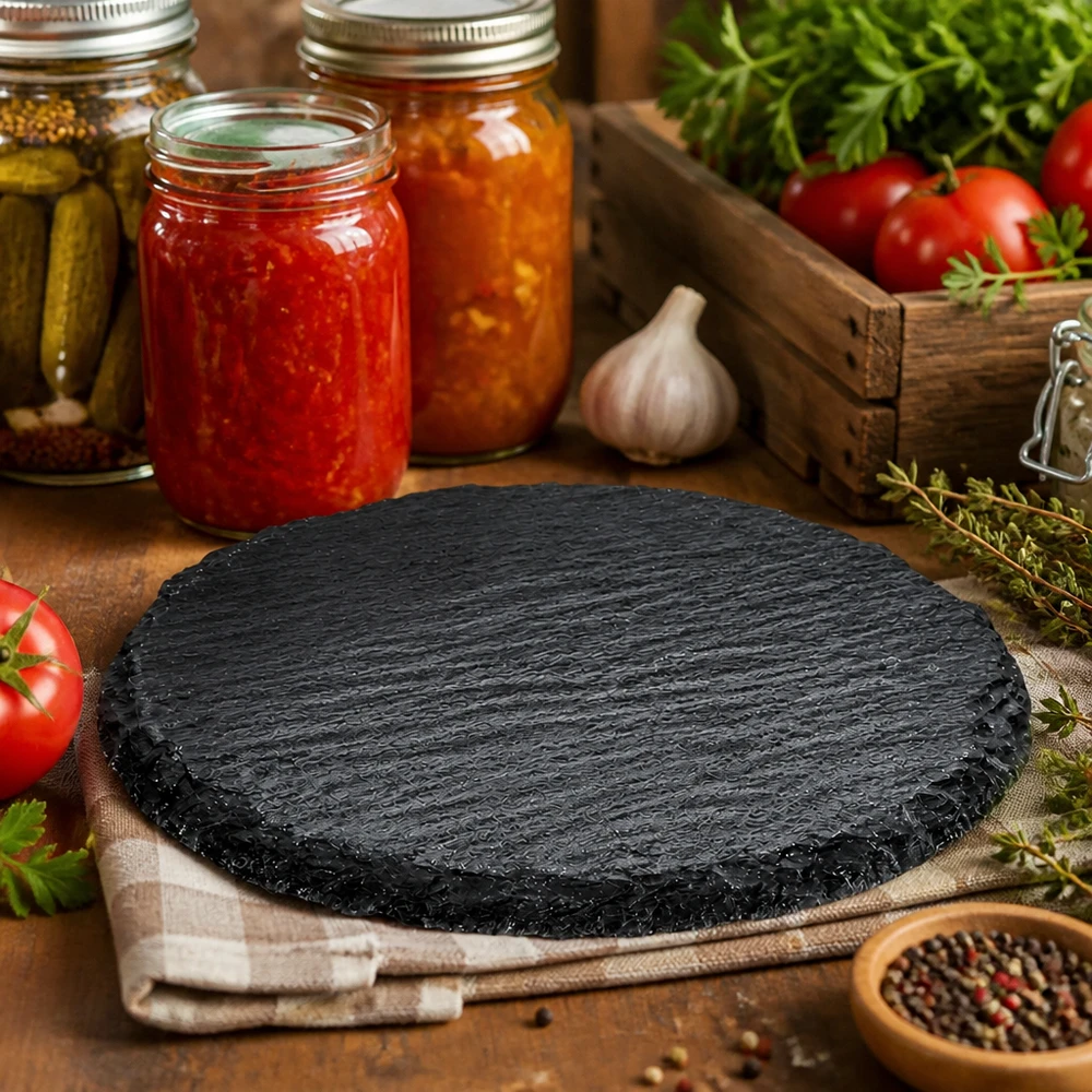 Plaque d'ardoise ronde 150mm dans une cuisine rustique décorée avec des bocaux, des tomates et des herbes comme planche de service