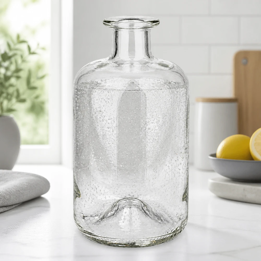 Flacon à pharmacie « 500ml Glasflasche "Luna" ohne Verschluss UNiTWIST » 500 ml sans bouchon UNiTWIST® Bouteille à pharmacie Luna 500ml avec texture de bulles sur un plan de travail de cuisine blanc à côté de citrons et de plantes