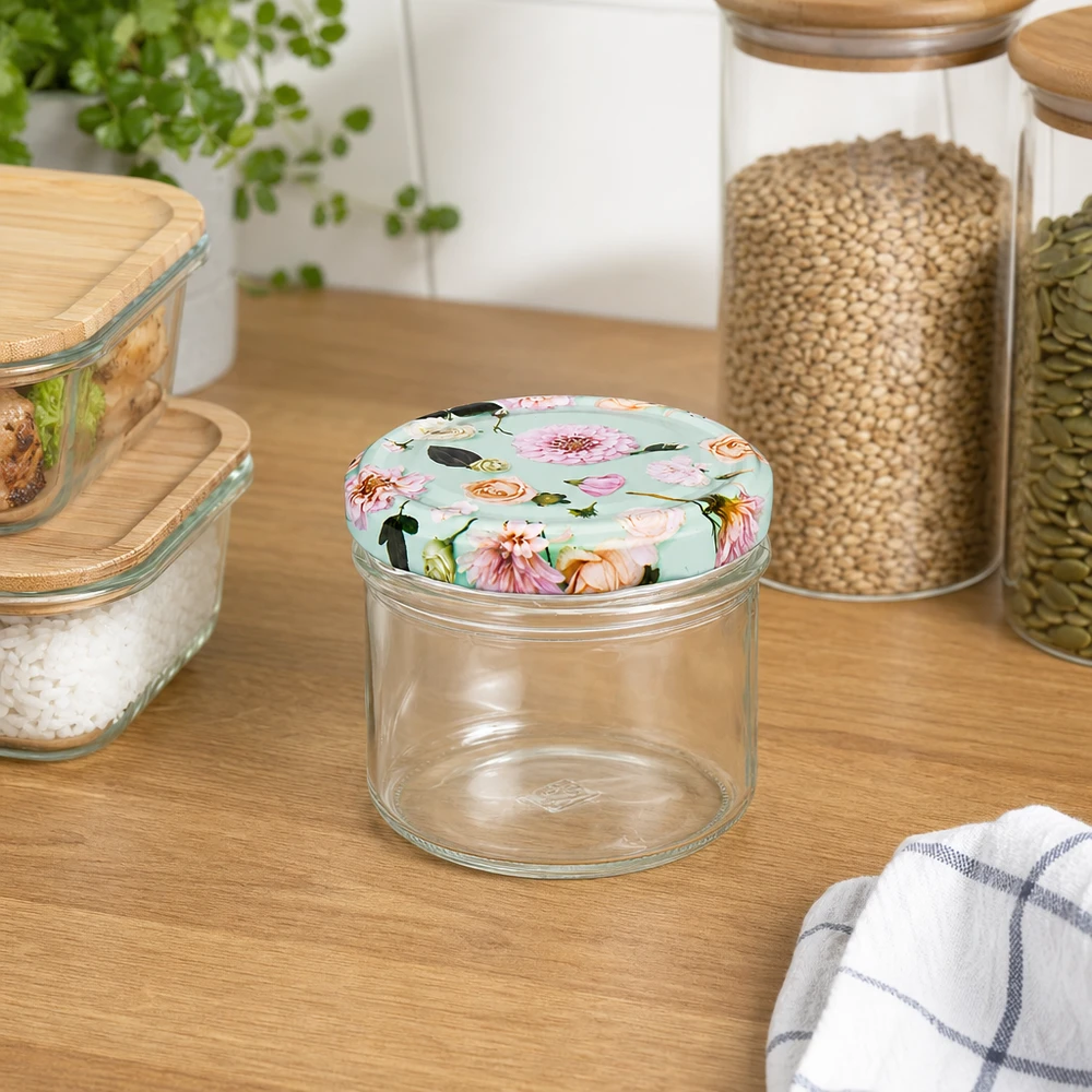 Verres de 180 ml + couvercle BasicSeal fleur de menthe UNiTWIST Pot vide de 225ml avec couvercle à fleur menthe sur comptoir en bois à côté de bocaux à provisions avec système UNiTWIST pour céréales